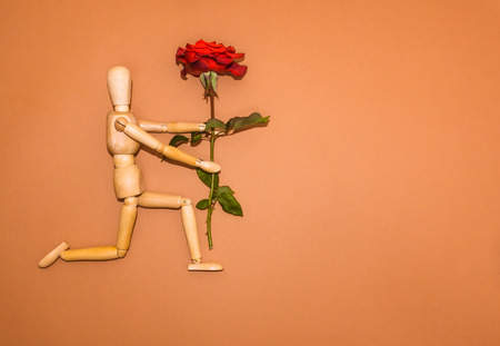 Red rose and figure wooden man on brown backgroundの写真素材