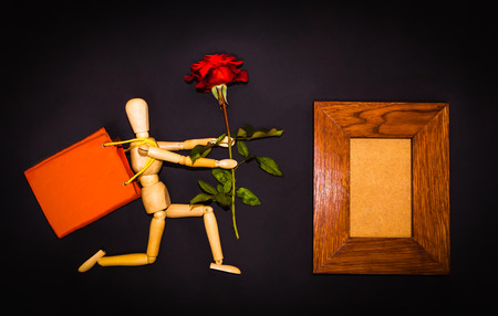 Red rose and figure wooden man on black backgroundの写真素材