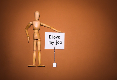 The wooden man with hand, holding the holder with text - I love my jobの写真素材