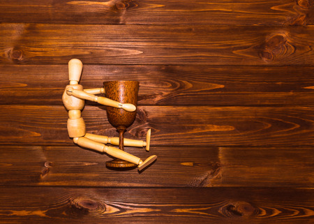 Wooden man with glass of wine on wooden backgroundの写真素材