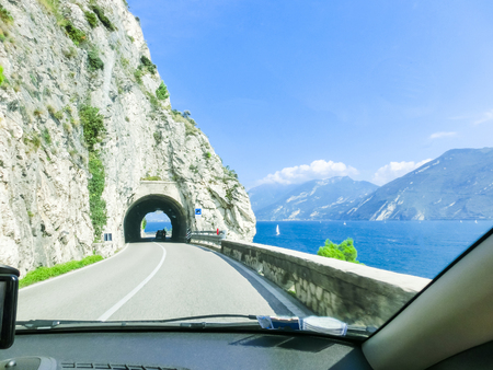 High mountains and road on the shore, Lake Garda, Italy, Europe. view through the windshield of carの写真素材