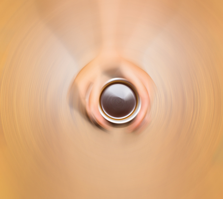 Female hands holding cup of coffee on wooden background, blurred in postproductionの写真素材