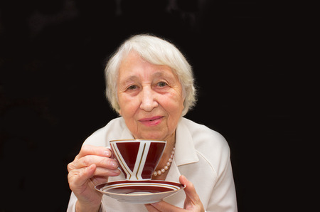 The Senior Woman Enjoying Cup Of Tea on blackの写真素材