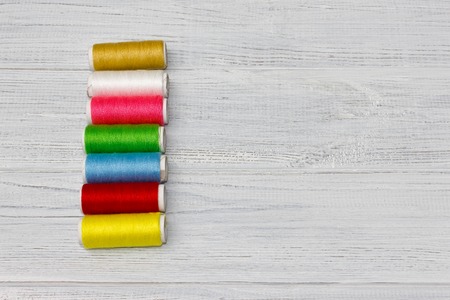 Bobbins with colorful threads on old wooden table background, Sewing background with copy space