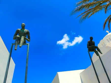 Oia, Santorini, Greece - June 10, 2015: Sculpture of sitting men as decoration of old building in Oia townのeditorial素材