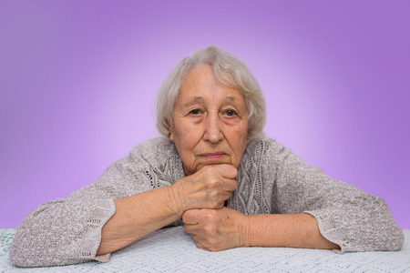 Senior grey haired woman dreaming isolated on blue backgroundの写真素材