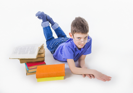 Portrait of cute schoolboy sitting with books and typing on laptop keyboardの写真素材