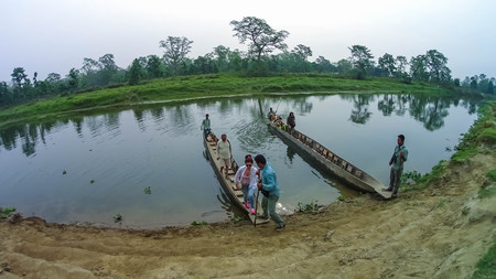 CHITWAN, Nepal - April 09, 2018: Unidentified people canoeing safari on wooden boats Pirogues on the Rapti river, in Chitwan National Park, Nepalのeditorial素材
