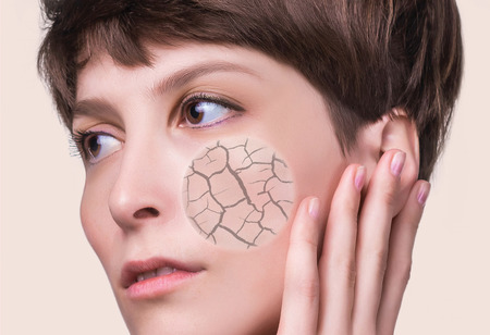 Woman face covered with cracked earth texture- symbol of dry skin. Problems of dehydrated female skinの写真素材