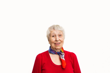 Old smiling woman with surprised expression on her face on studio background. Human emotions concept. Positive emotional old lady standing indoorの写真素材