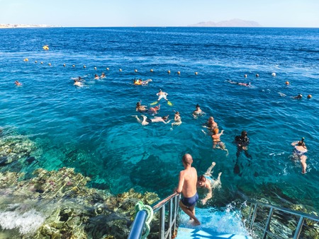 Sharm El Sheikh, Egypt - December 31, 2018: The people snorkeling in blue waters above coral reef on...