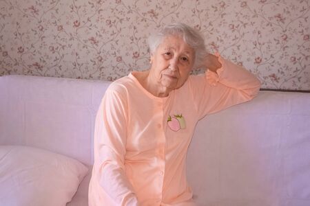 Coronavirus, Covid-19, health, safety and pandemic concept, care, pain, stress, age and people concept - face of senior woman suffering from headache at homeの写真素材