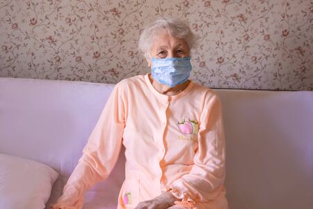 Coronavirus, Covid-19, health, safety and pandemic concept, care, pain, stress, age and people concept - face of senior woman suffering from headache at homeの写真素材