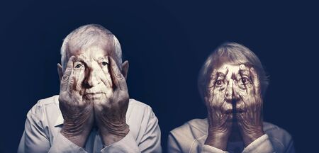 Portrait of an elderly couple with face closed by handsの写真素材