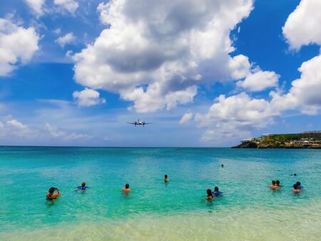 The beach at Maho Bay is one of the world's premier planespotting destinations. Airplanes landing at the Princess Juliana Airport fly over beachgoers.の写真素材