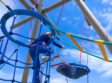 The girl climbing in adventure rope park against blue sky