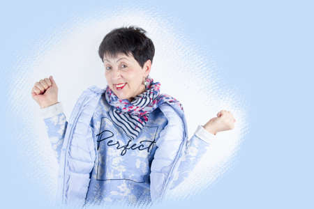 portrait of a cheerful senior woman gesturing victory over blue studio background