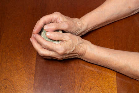 Senior woman holding dollar cash. Old female with money in hands on table