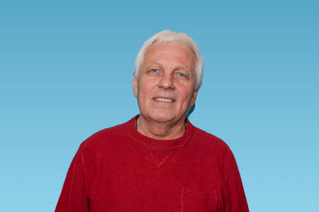 Senior handsome man with gray hair at home standing and smiling against blue studio. Human emotions...