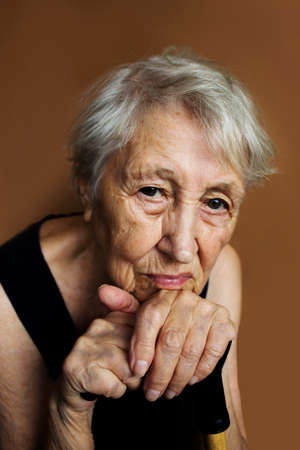 The face and eyes of an old sad woman. She sitting at home and looking to camera. Human problems and...
