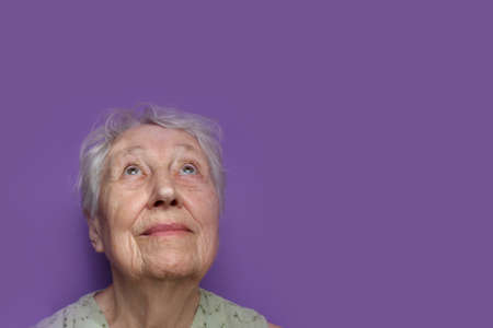 Smiling senior woman on lilac studio background. Hope and dreams conceptの写真素材