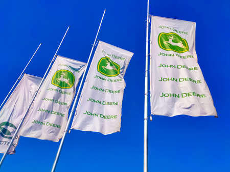 Kyiv, Ukraine - August 24, 2020: John Deere logo at flags at road at Kyiv, Ukraine on August 24,...
