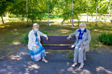 The sad senior women in social distancing sitting at park. The Covid-19, health, safety and pandemic conceptの写真素材