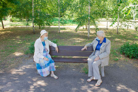 The senior women in social distancing sitting at park. The Covid-19, health, safety and pandemic conceptの写真素材