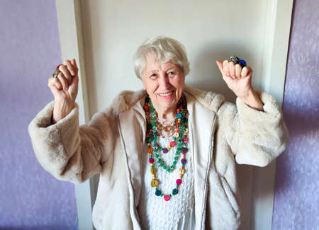 Happy smiling funny senior woman wearing beads dancing at home