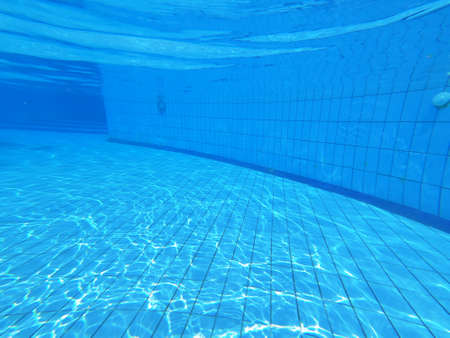 Blue pool water with sun reflections at sunny day