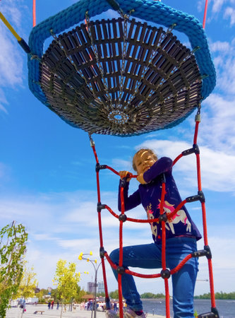 The girl climbing in adventure rope park against blue skyの写真素材