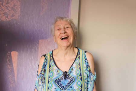 The portrait of a cheerful smiling senior woman over home backgroundの写真素材