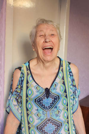 The portrait of a cheerful smiling senior woman over home backgroundの写真素材