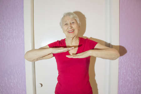 Senior woman wearing sportswear while gymnastic exercising in the living room at home.