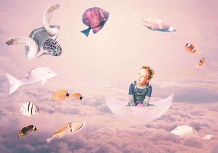 Make my wishes. Mixed media. Creative art collage about childhood and dream concept. Underwater world and coral fish. Conceptual image about beautiful girl floating in a boat among the cloudsの写真素材