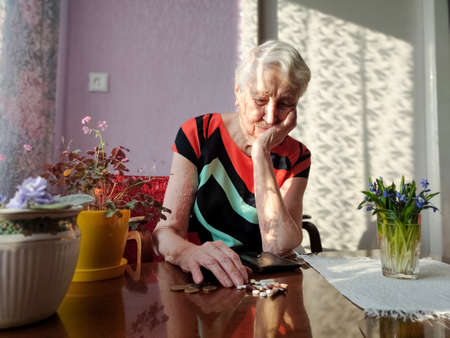 Senior woman sitting at home with pills. Poverty concept. All money was spent for pillの写真素材