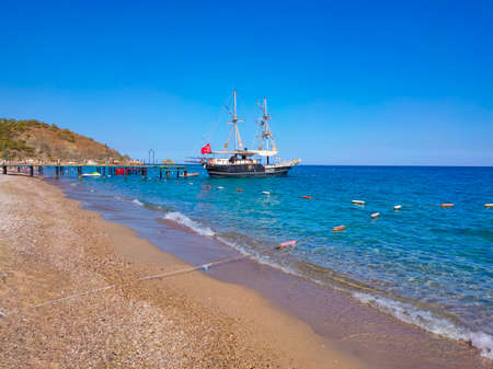 Tekirova, Antalya, Turkey - May 11, 2021: Bay in mediterranean sea with old yacht and fun sun in Turkey.のeditorial素材
