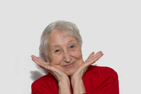 The portrait of a cheerful smiling senior woman gesturing victory over studio backgroundの写真素材