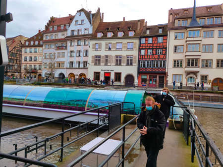 Strasbourg, Alsace, France - December 30, 2021: River tram with tourists on a water canal on ancient houses background. river view. Strasbourg city, France. Famous tourist destination, travel, tourismのeditorial素材
