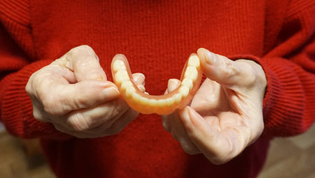 flexible nylon denture on senior female hands. Removable dentures flexible, devoid of nylon,...