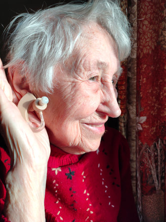 Middle age woman smiling confident using hearing aid at homeの写真素材