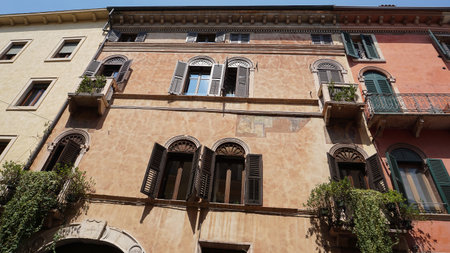 Beautiful traditional Italian building with flowers on balcony of medieval wall at Verona, Italyの写真素材