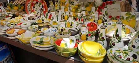 Hand-painted Italian ceramic tableware with lemon and olive motifs on display at a street market in Verona, Italy. Traditional crafts and souvenirs.の写真素材
