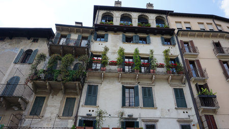 Beautiful traditional Italian building with flowers on balcony of medieval wall at Verona, Italyの写真素材