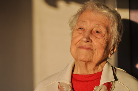 The portrait of a cheerful smiling senior woman over home background
