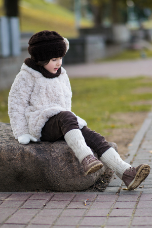 Little fashionable girl in warm clothes in the cityの写真素材