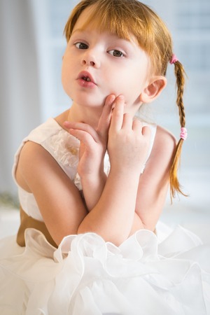 Red haired girl of six years in a white dressの写真素材