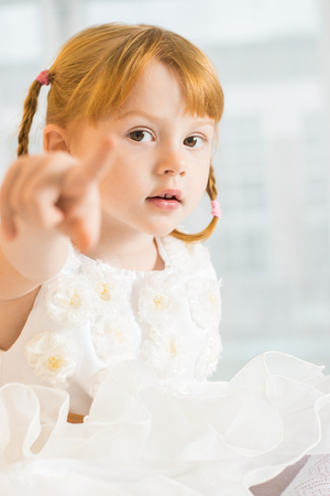 Red haired girl of six years in a white dressの写真素材