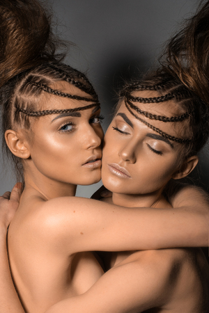 Portrait of gorgeous twins in studio over grey background togetherの写真素材