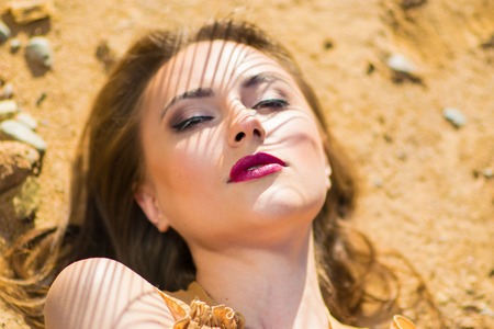 Beautiful woman lying on stones with opened eyes. Very hot sexual girl. Beauty fashion style.の写真素材